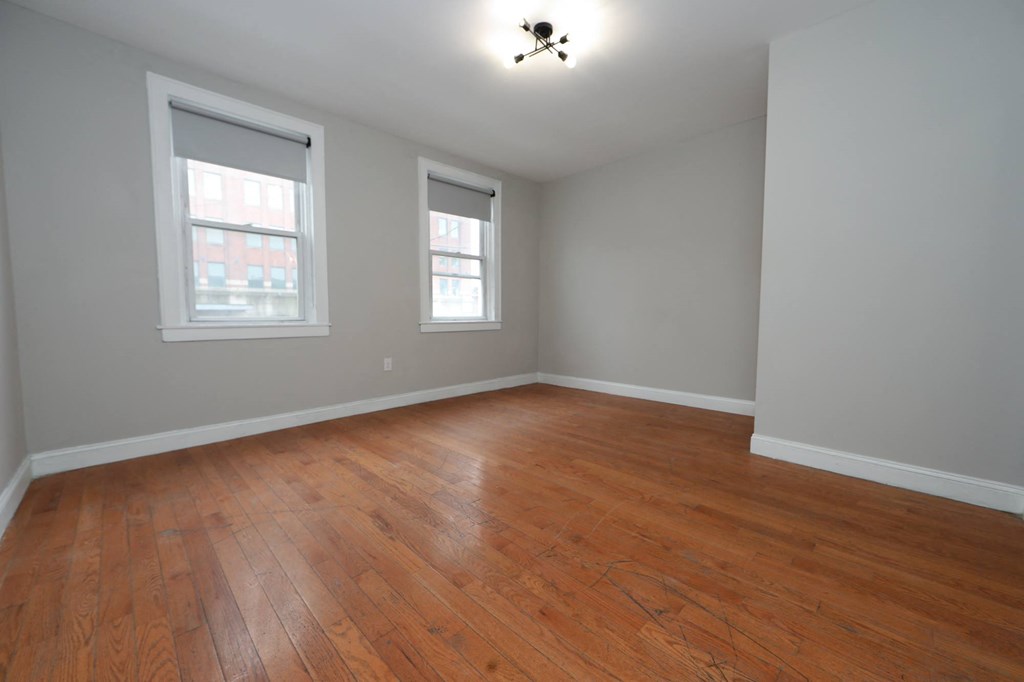 an empty living room with wood floors and two windows