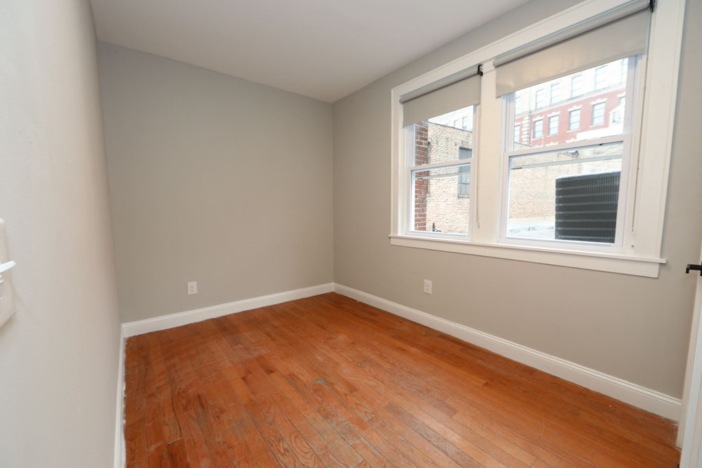 a bedroom with a wood floor and a large window