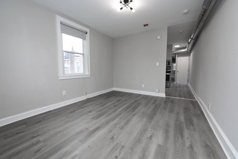 the living room is spacious and has a large window and wood flooring