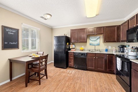 A kitchen with wooden cabinets and a black refrigerator.