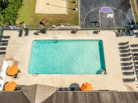 An aerial view of a swimming pool surrounded by lounge chairs and umbrellas.