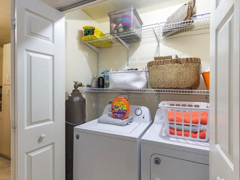 A laundry room with a washer and dryer, a basket, and some containers.