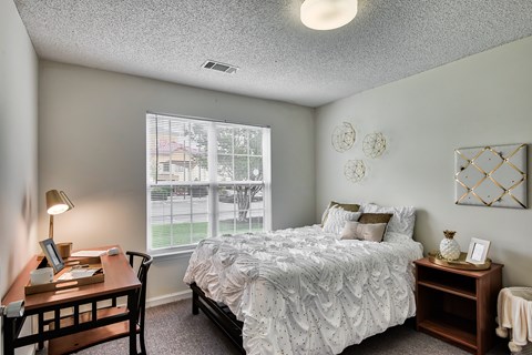 A bedroom with a bed, nightstand, and window.
