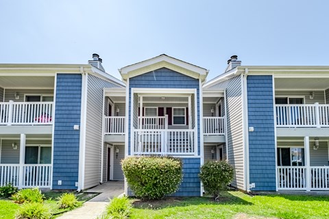 A blue and white building with a red car parked in front.