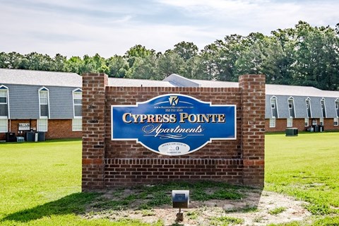 A sign for Cypress Pointe Apartments is displayed in front of a grassy area.