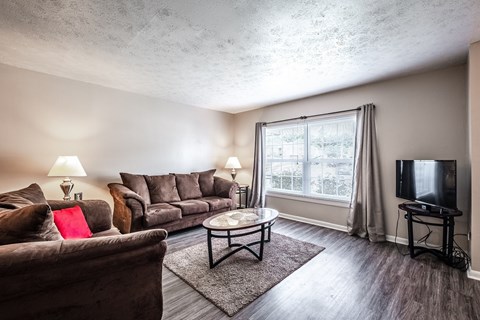A living room with a brown couch, a coffee table, and a flat screen TV.