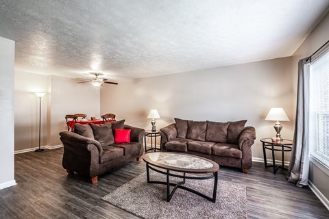 A living room with a brown couch, a coffee table, and a lamp.