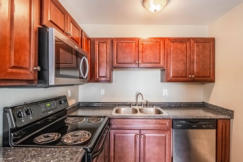 A kitchen with wooden cabinets and a black stove top oven.