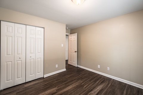 A room with a white door and a brown floor.