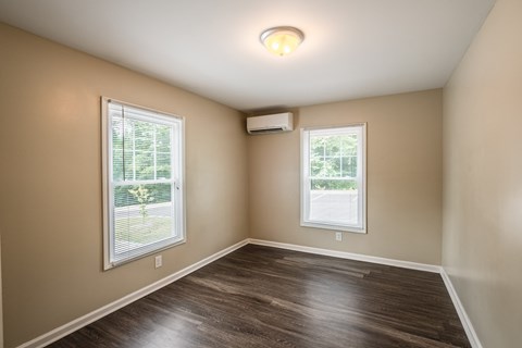 A room with a window and a wall-mounted air conditioner.