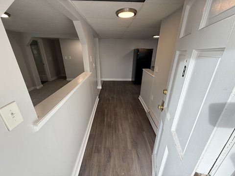 A hallway with a white door and a mirror on the wall.