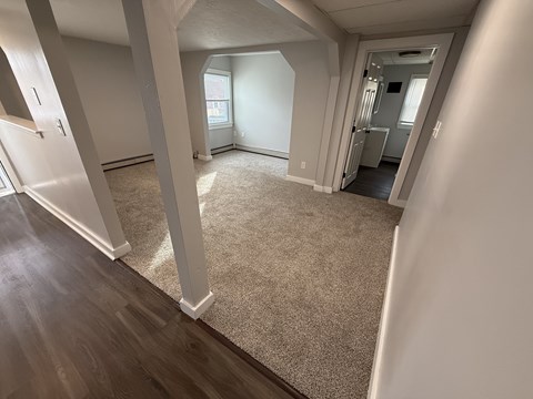 A spacious room with a carpeted floor and wooden flooring.