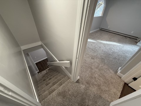 A staircase with a carpeted floor and a white wall.