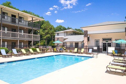 A large swimming pool surrounded by lounge chairs and umbrellas.