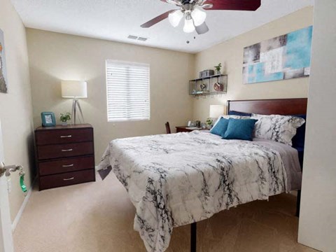 A bedroom with a marble bedspread and a ceiling fan.