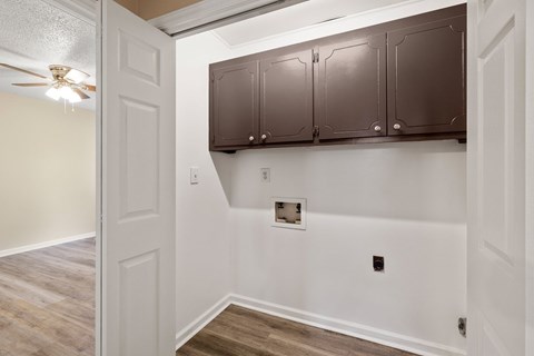 A white wall with a brown cabinet and a ceiling fan.