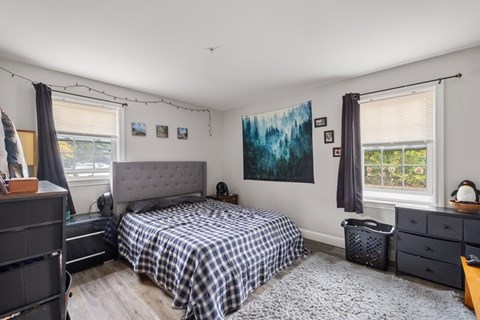 A bedroom with a bed, dresser, and window.