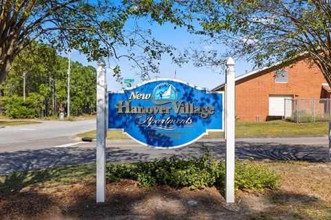 A blue sign for New Harbor Village Spirits stands in front of a building.