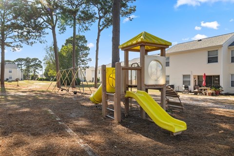 A playground with a yellow slide and a yellow and brown wooden structure.