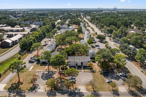 A bird's eye view of a residential area with houses, trees, and parked cars.