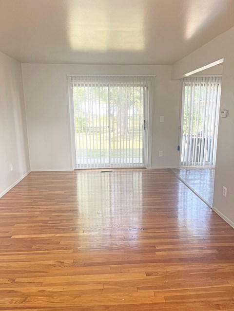 an empty living room with wooden floors and a sliding glass door