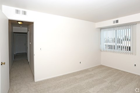 an empty living room with a large window and white walls