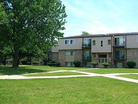 an exterior view of an apartment building with grass and trees