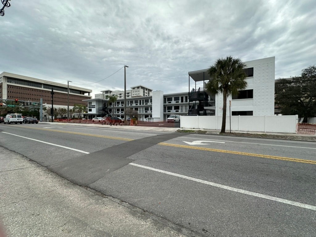 an empty street in front of a building with a palm tree
