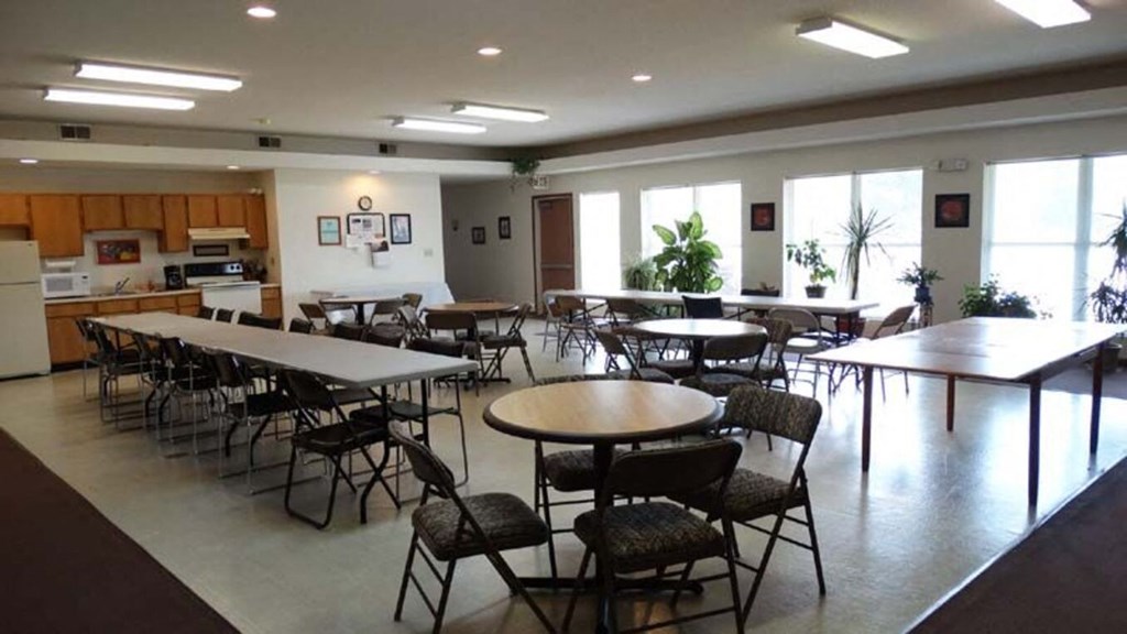 a dining room with tables and chairs and a kitchen
