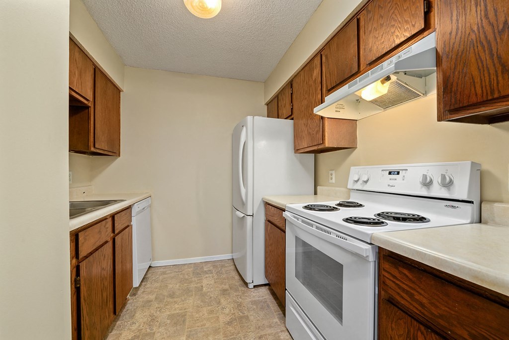 a kitchen with white appliances and wooden cabinets and a refrigerator