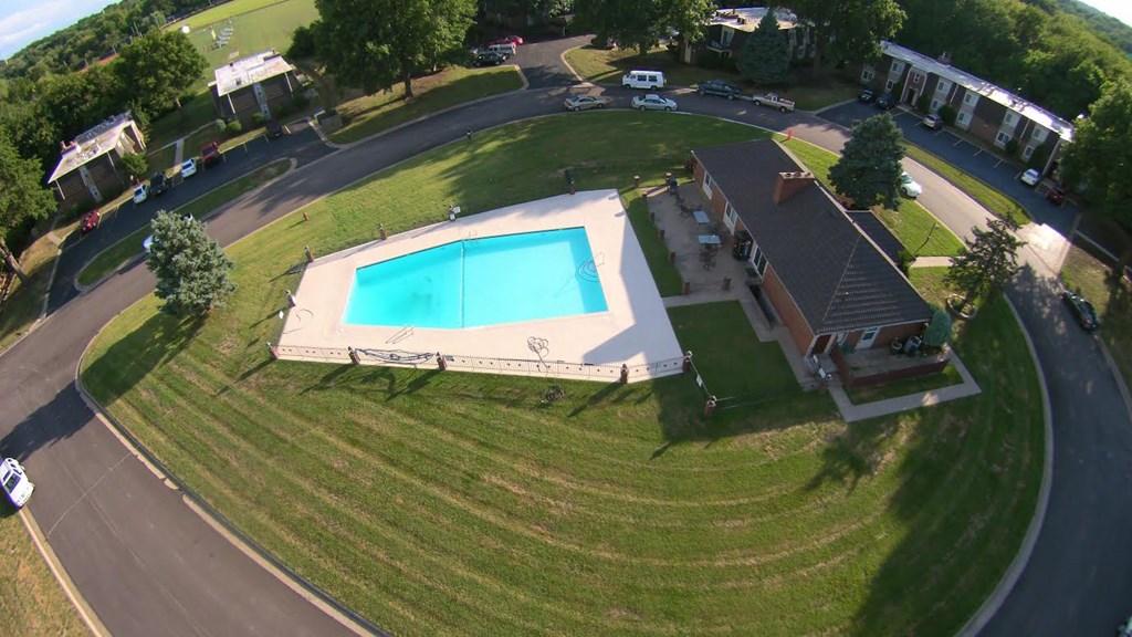 A swimming pool in a grassy area surrounded by a road.