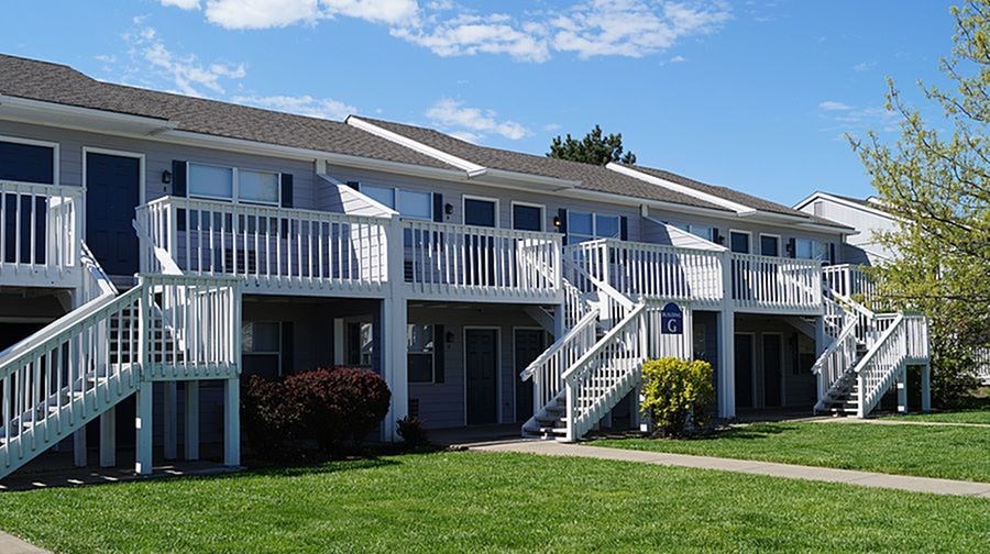 A row of houses with white railings and steps leading to the doors.