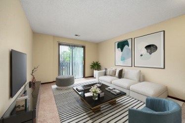 A living room with a white couch, a blue armchair, a coffee table, and two framed pictures on the wall.