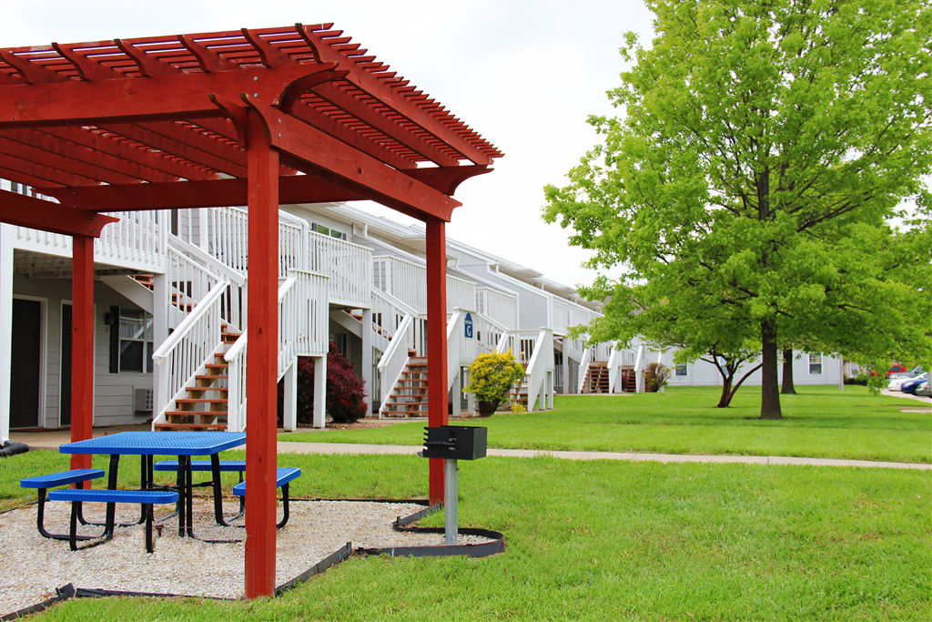 A red pergola is in front of a white building.