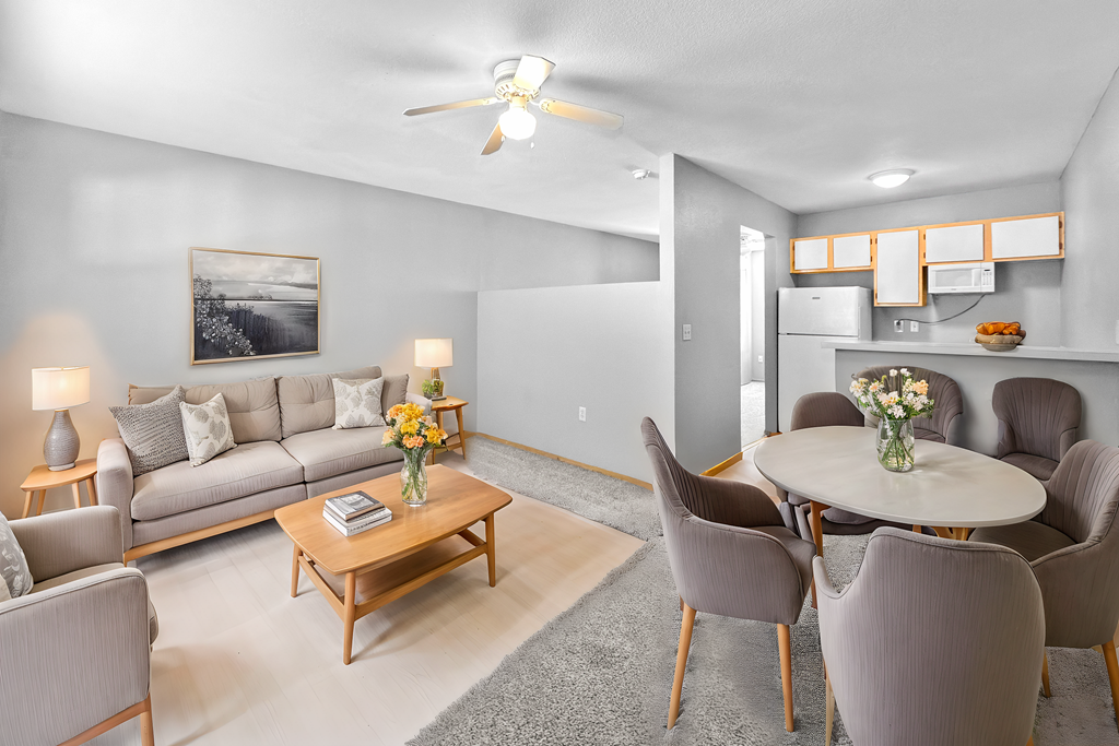 A living room with a grey couch, a coffee table, and a dining table with chairs.