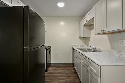 A kitchen with a black refrigerator and white cabinets.