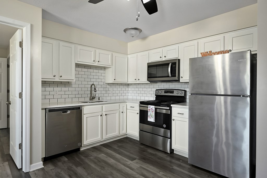 A kitchen with a refrigerator, oven, and microwave.