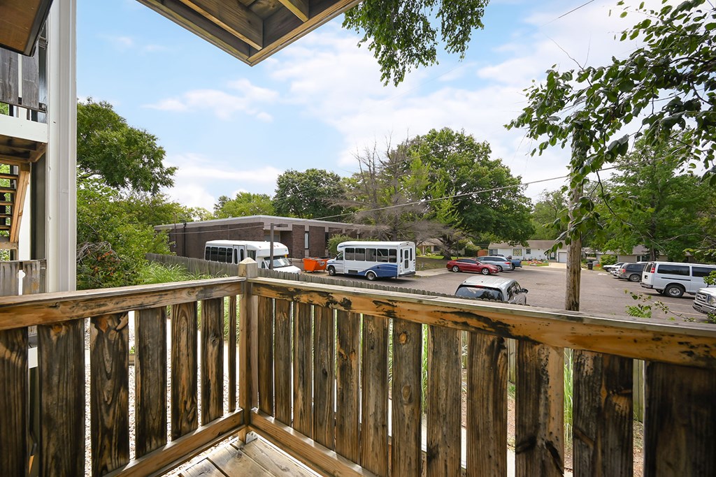 A view from a balcony overlooking a parking lot and a building.