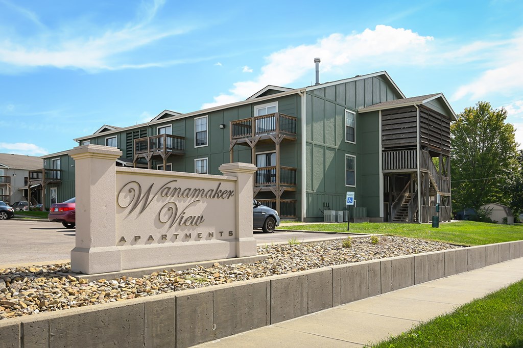 A large building with the name Wanamaker View Apartments on a stone pillar in front.