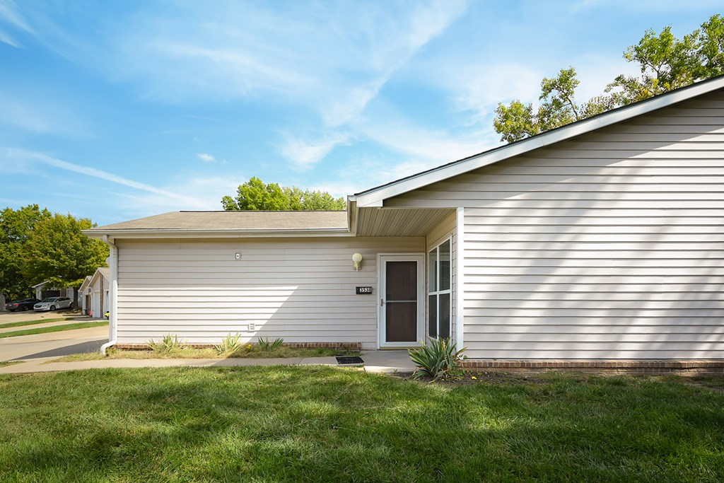 A house with a white siding and a brown roof with a small front yard.