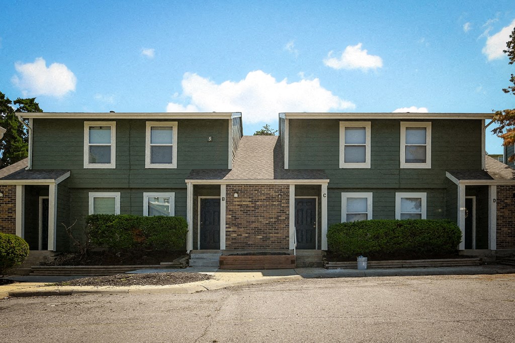 a green house with a street in front of it