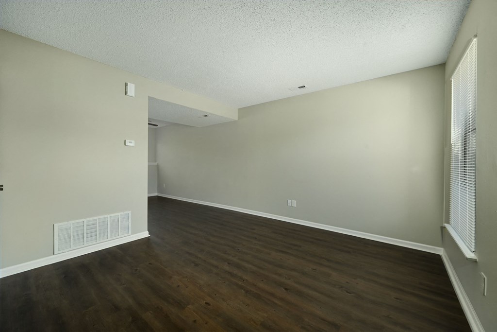 an empty living room with wood flooring and white walls