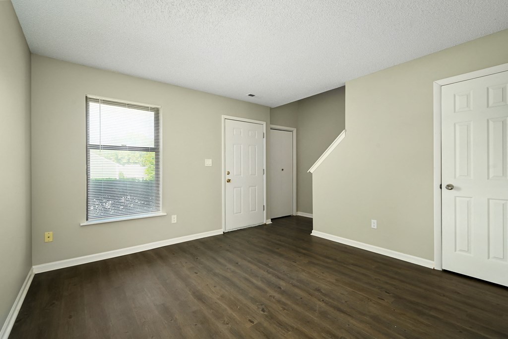an empty living room with wood flooring and a window