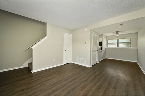 an empty living room with hardwood floors and white walls