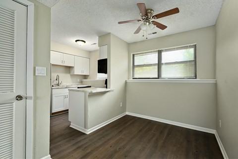 an empty kitchen and living room with a ceiling fan