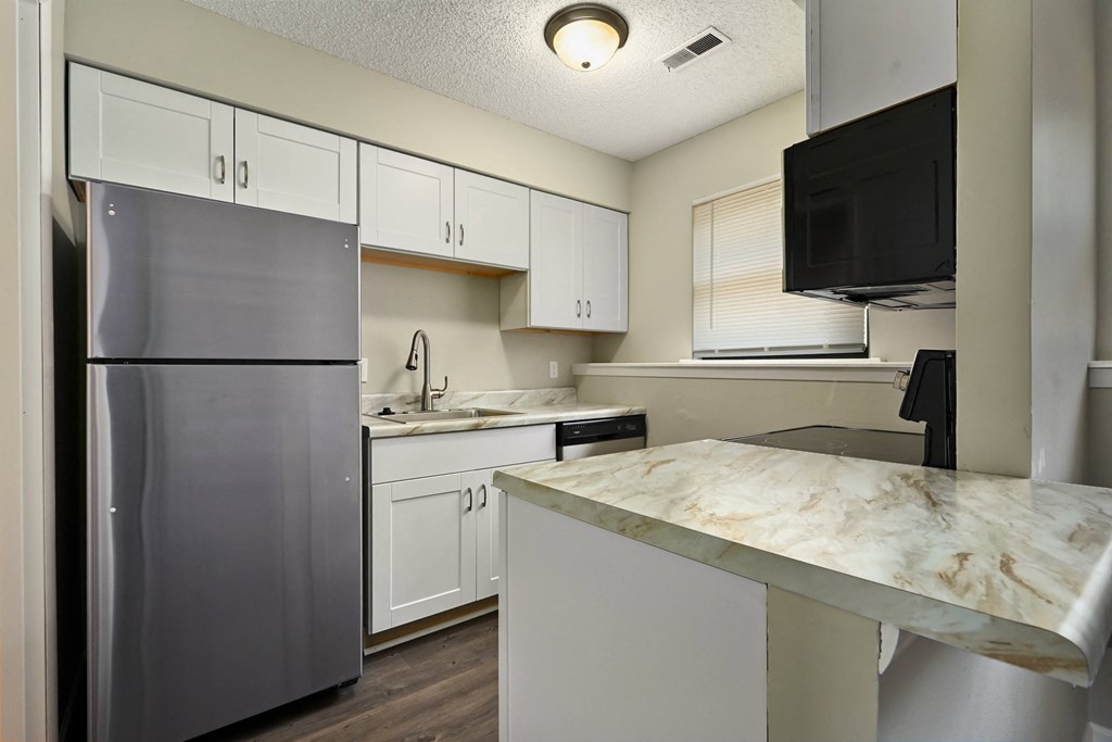 a kitchen with white cabinets and stainless steel appliances and a marble counter top