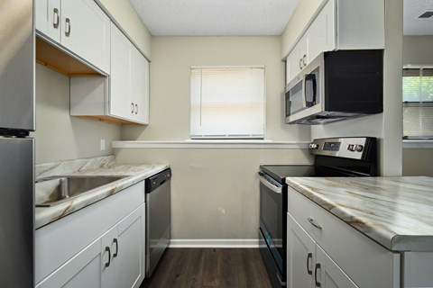 an empty kitchen with white cabinets and stainless steel appliances