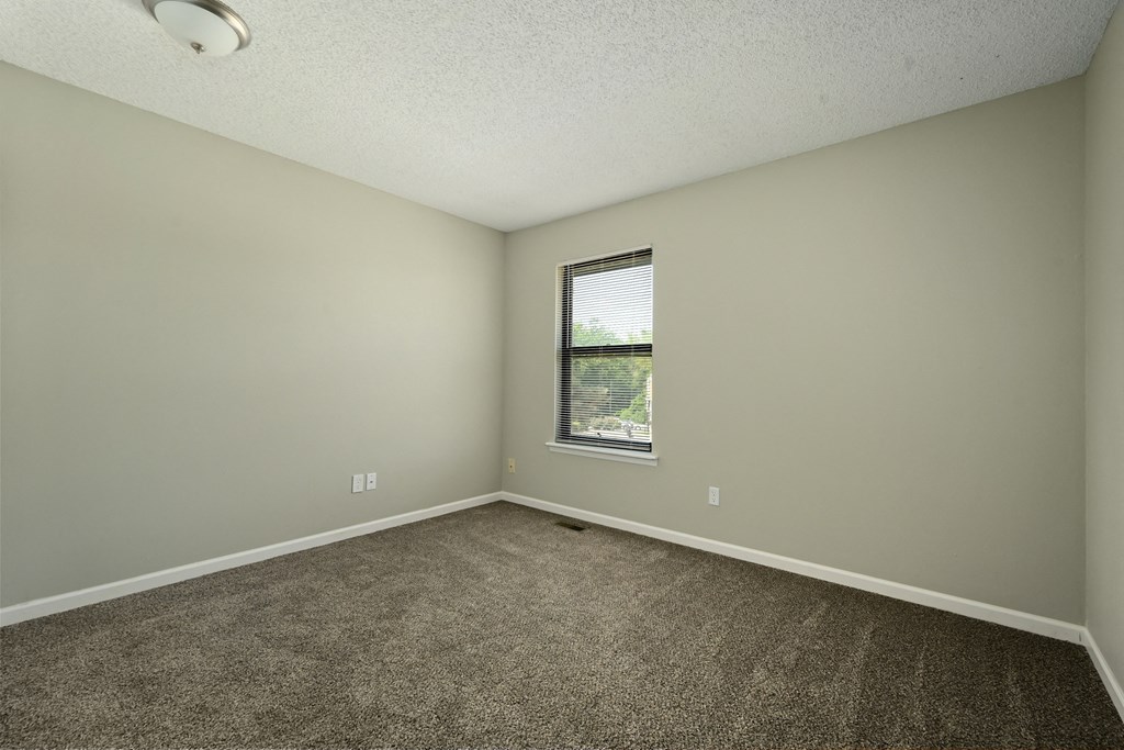 an empty room with carpet and a window