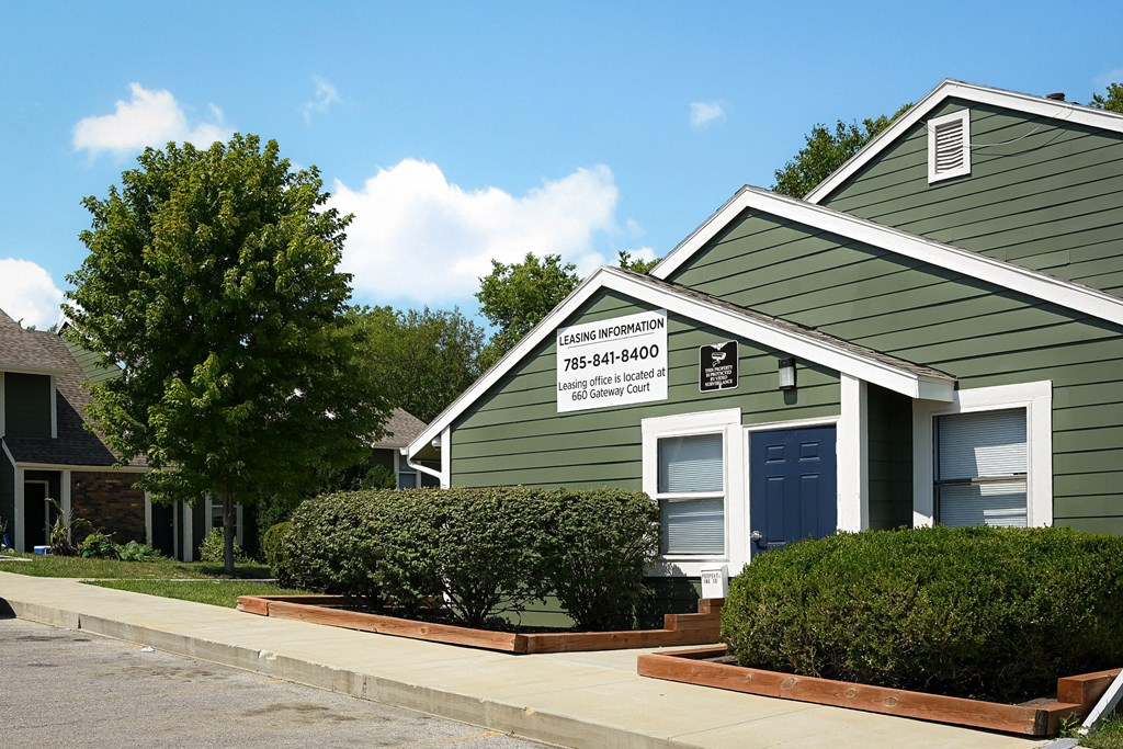 a green house with a blue door and a sign on it