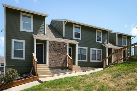 a row of green houses with stairs and a yard